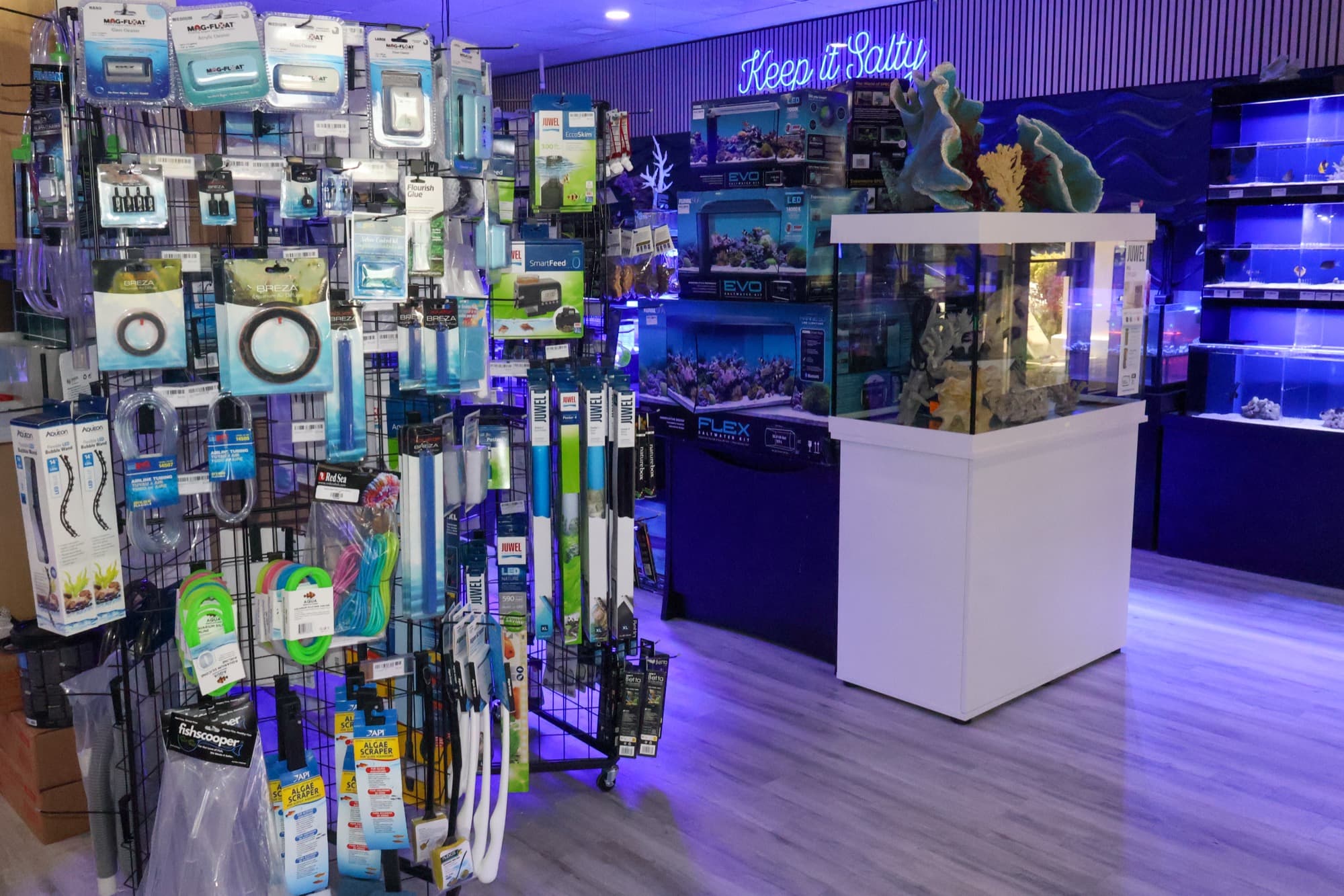 A display aquarium on its cabinet on the Barrier Reef store floor, with the livestock systems behind it